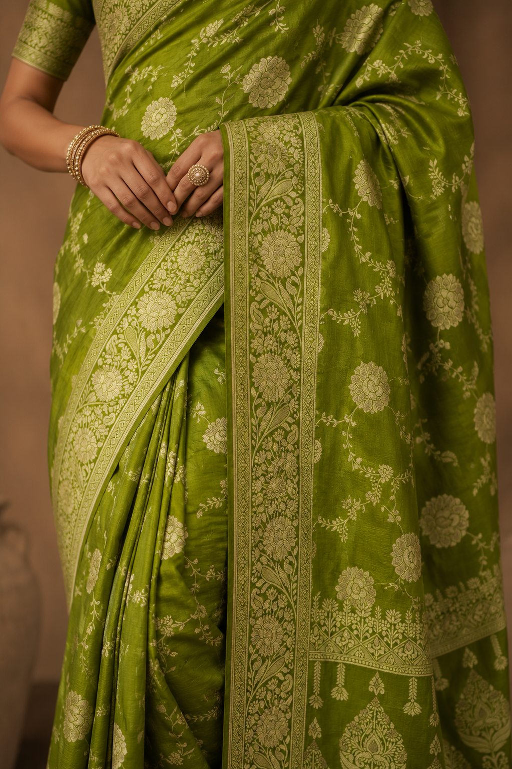 Close-up of olive green Dola silk saree featuring detailed zari floral weaving and decorative border.