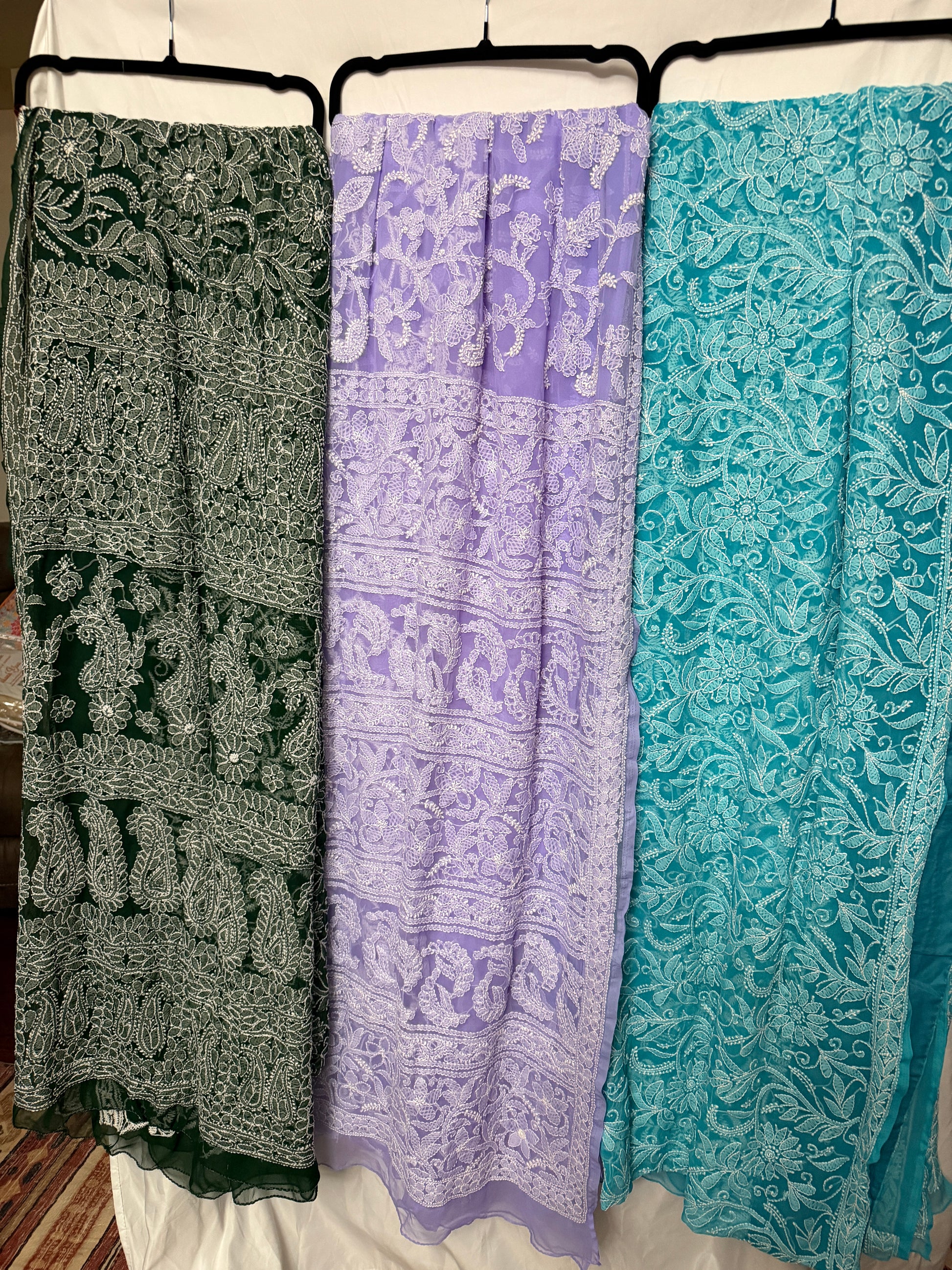 Women's pure georgette embroidered saree collection featuring six elegant colors—green, blue, purple, maroon, dark green, and peach—with intricate white floral embroidery and paisley motifs.