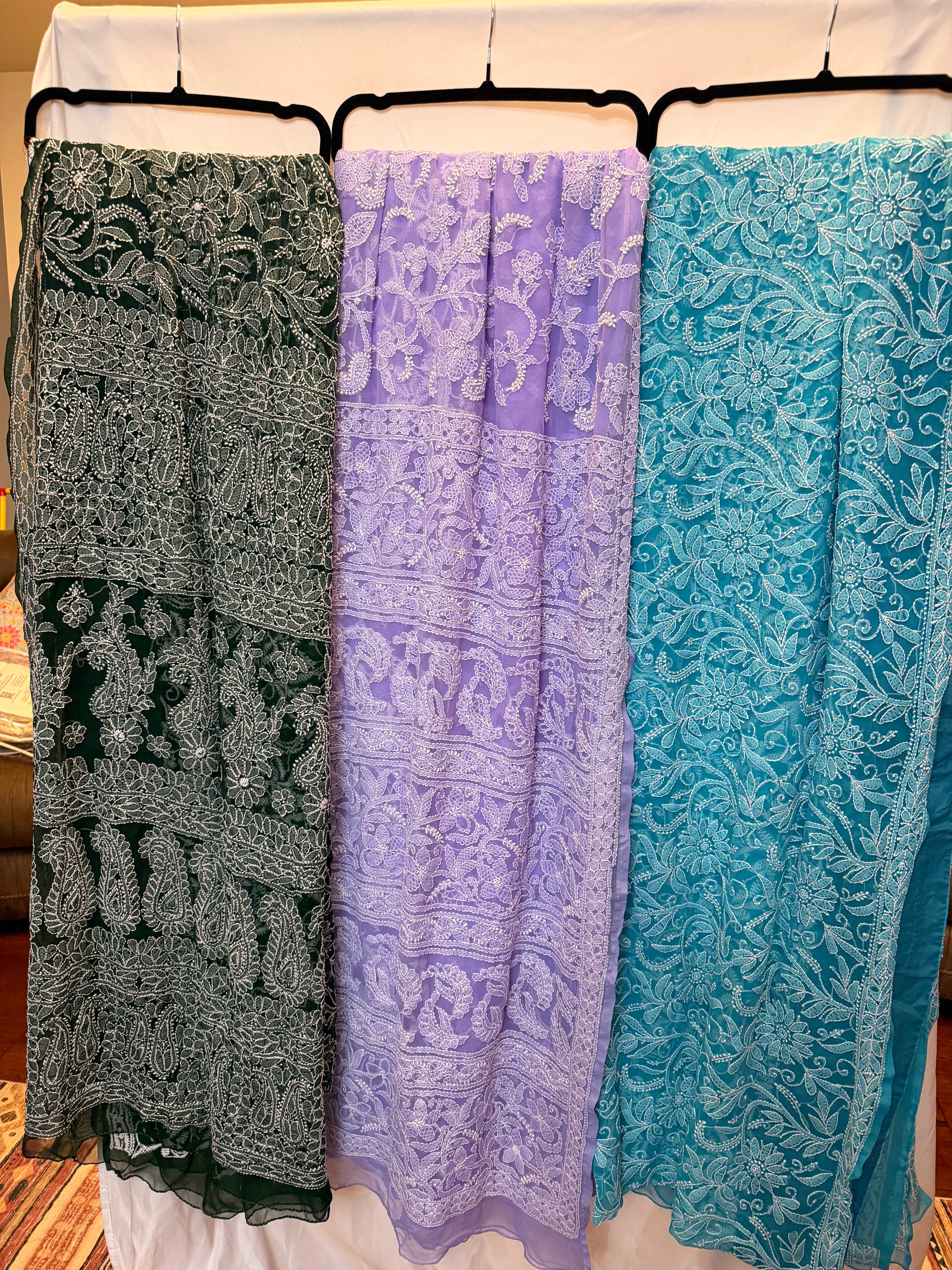 Women's pure georgette embroidered saree collection featuring six elegant colors—green, blue, purple, maroon, dark green, and peach—with intricate white floral embroidery and paisley motifs.