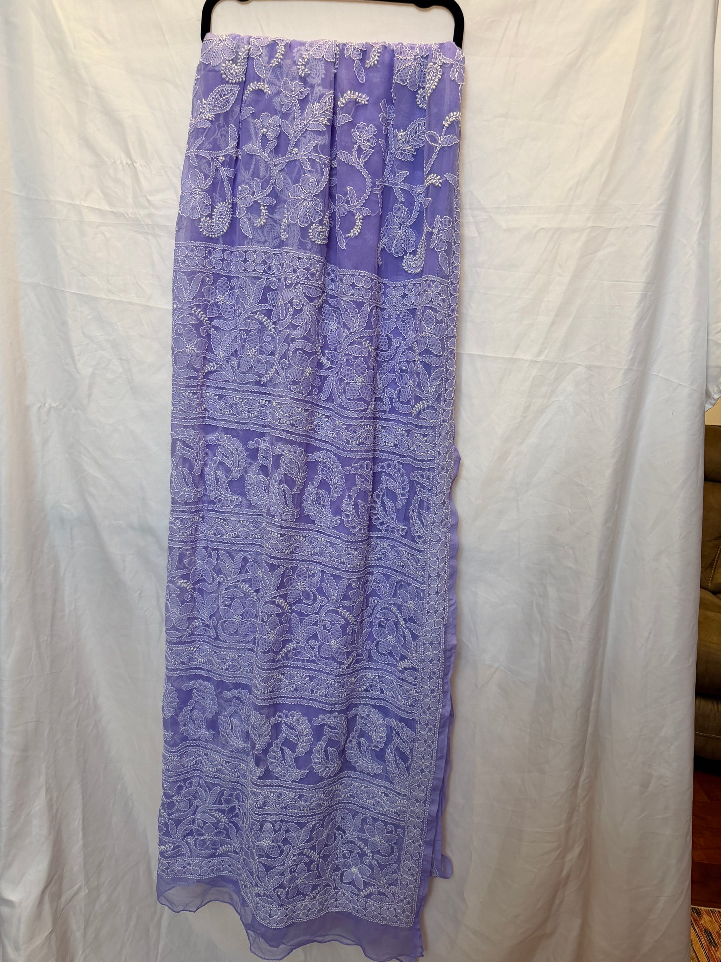 Close-up of a lavender purple pure georgette saree showcasing intricate white floral embroidery, paisley motifs, and elegant embroidered border.