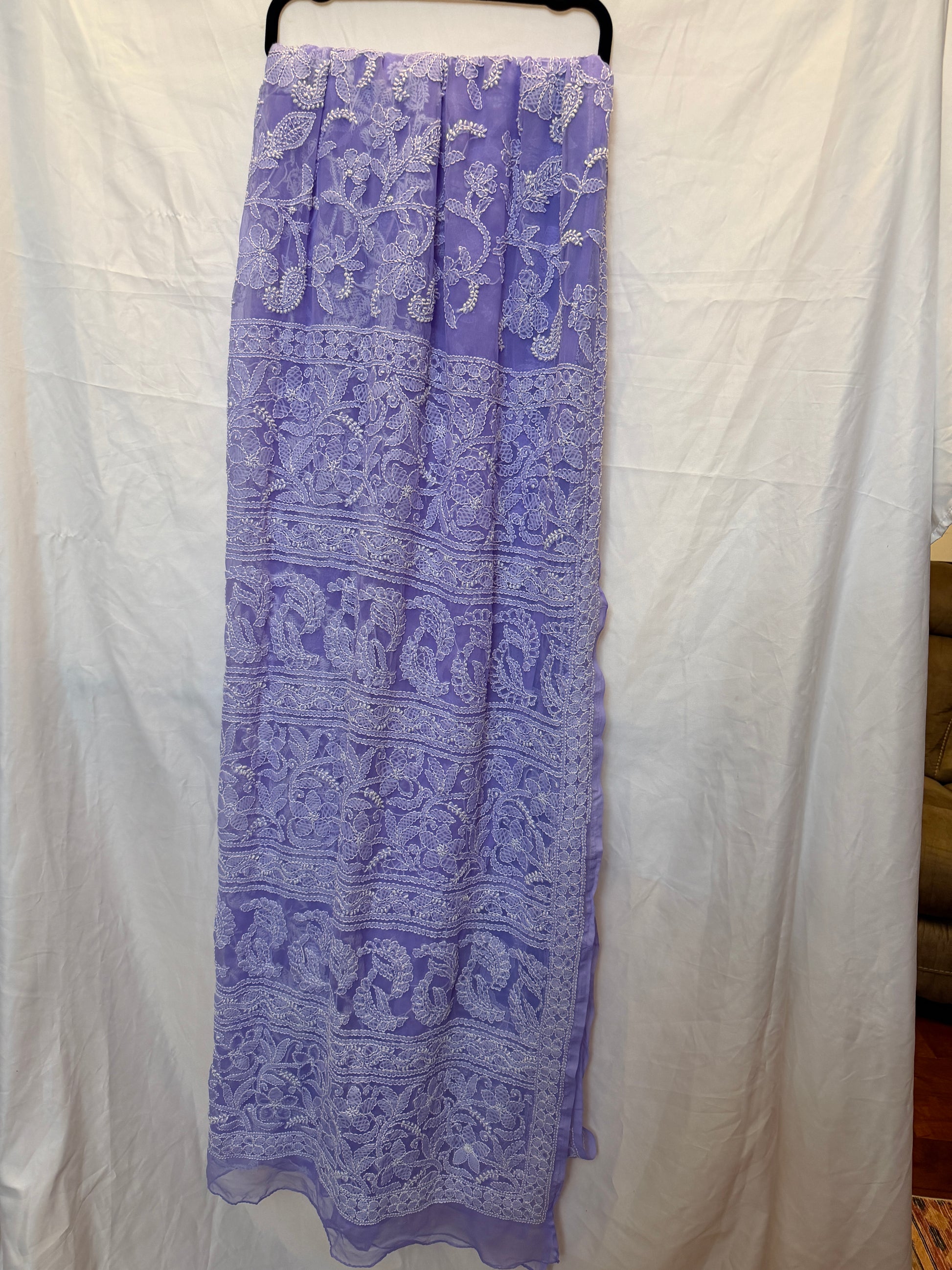 Close-up of a lavender purple pure georgette saree showcasing intricate white floral embroidery, paisley motifs, and elegant embroidered border.