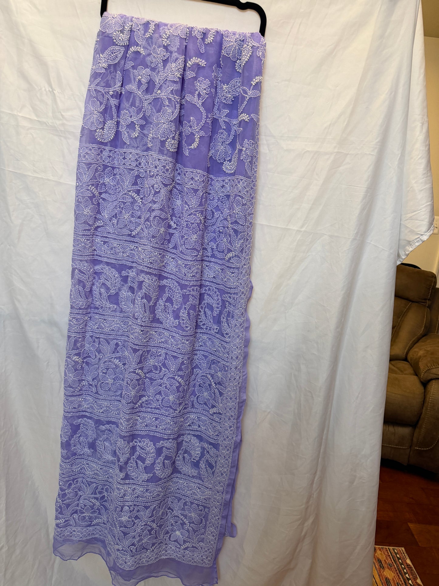 Close-up of a lavender purple pure georgette saree showcasing intricate white floral embroidery, paisley motifs, and elegant embroidered border.