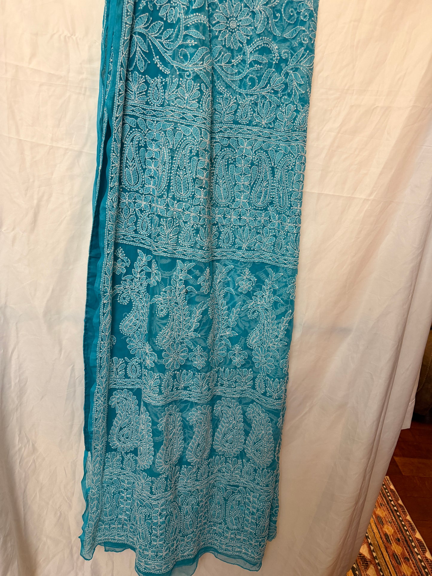 Close-up of a sky blue pure georgette saree highlighting intricate white floral embroidery, paisley motifs, and elegant embroidered border.