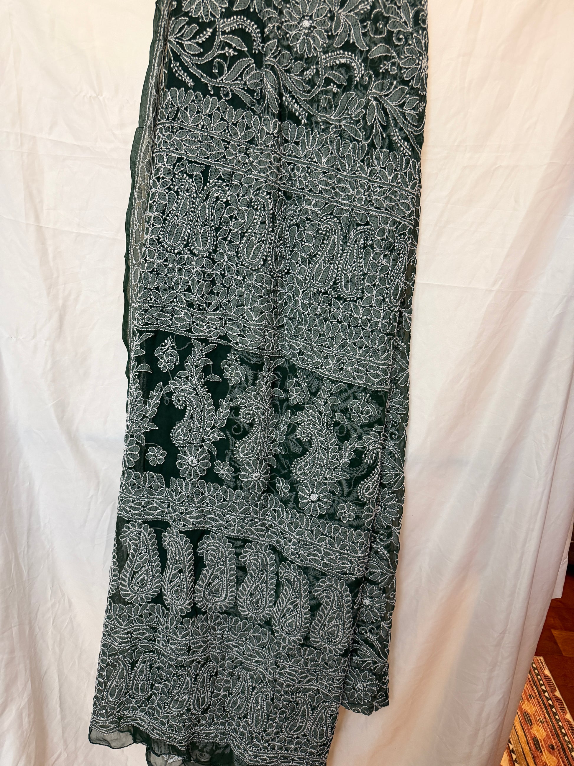 dark green pure georgette saree with detailed white floral embroidery and paisley motifs, styled with a matching embroidered blouse.