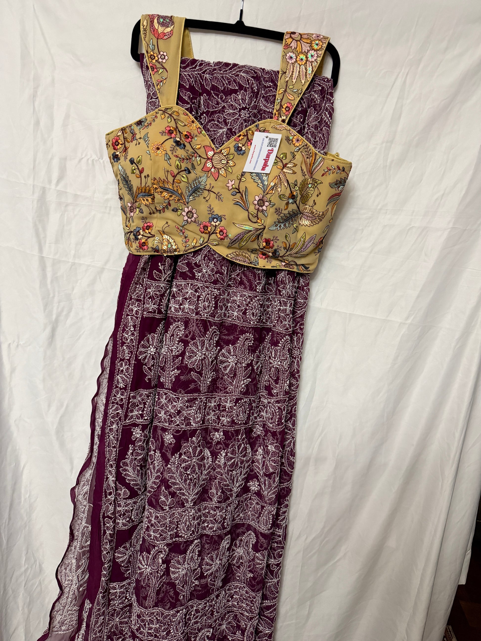 Close-up of a maroon pure georgette saree featuring delicate white floral embroidery, paisley motifs, and fine embroidered border detailing.