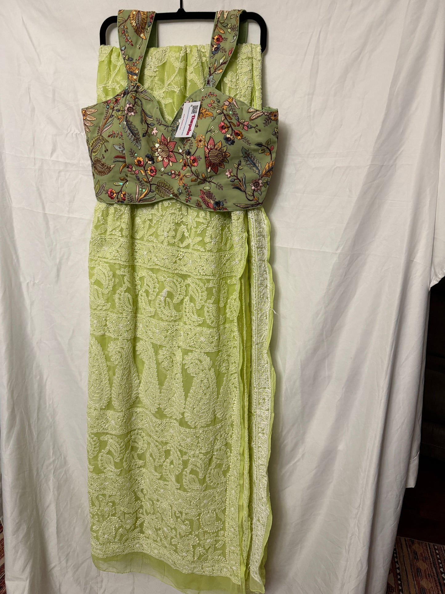 Close-up of a light green pure georgette saree showcasing intricate white floral embroidery, paisley motifs, and detailed embroidered border.