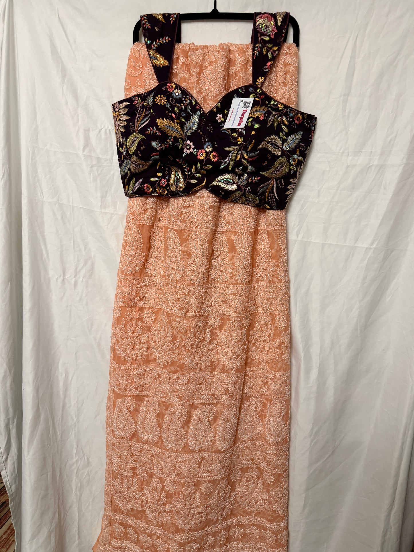 Peach pure georgette saree with intricate white floral embroidery and paisley motifs, paired with a black embroidered blouse.