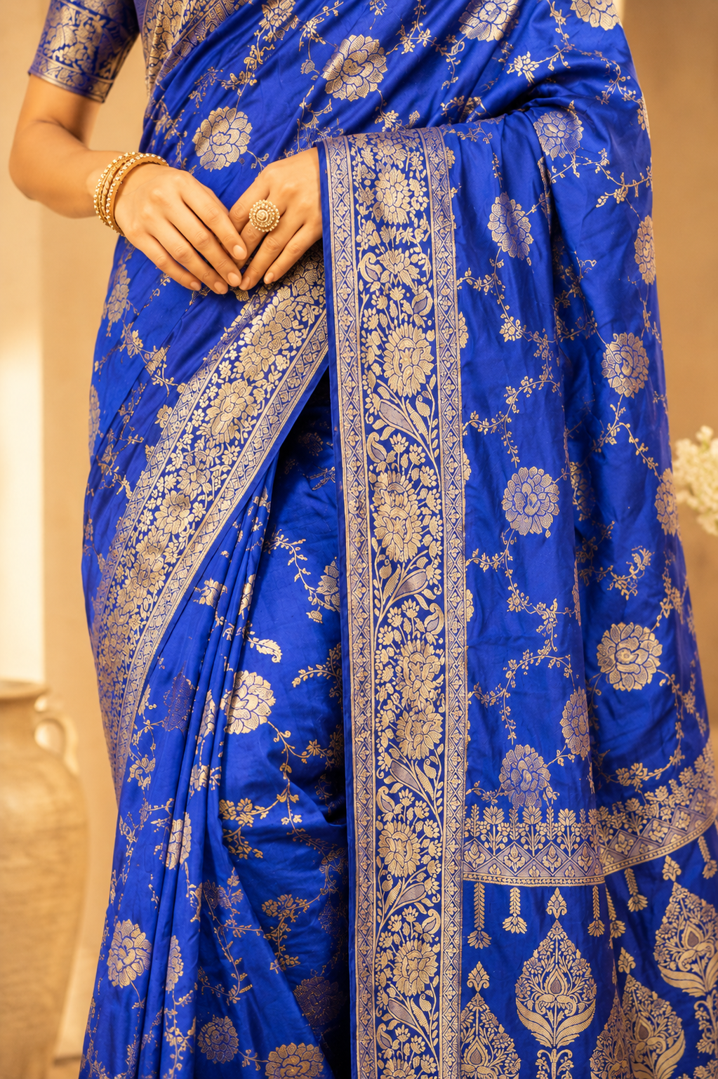 Close-up of royal blue Dola silk saree showcasing intricate gold zari floral border and woven craftsmanship.