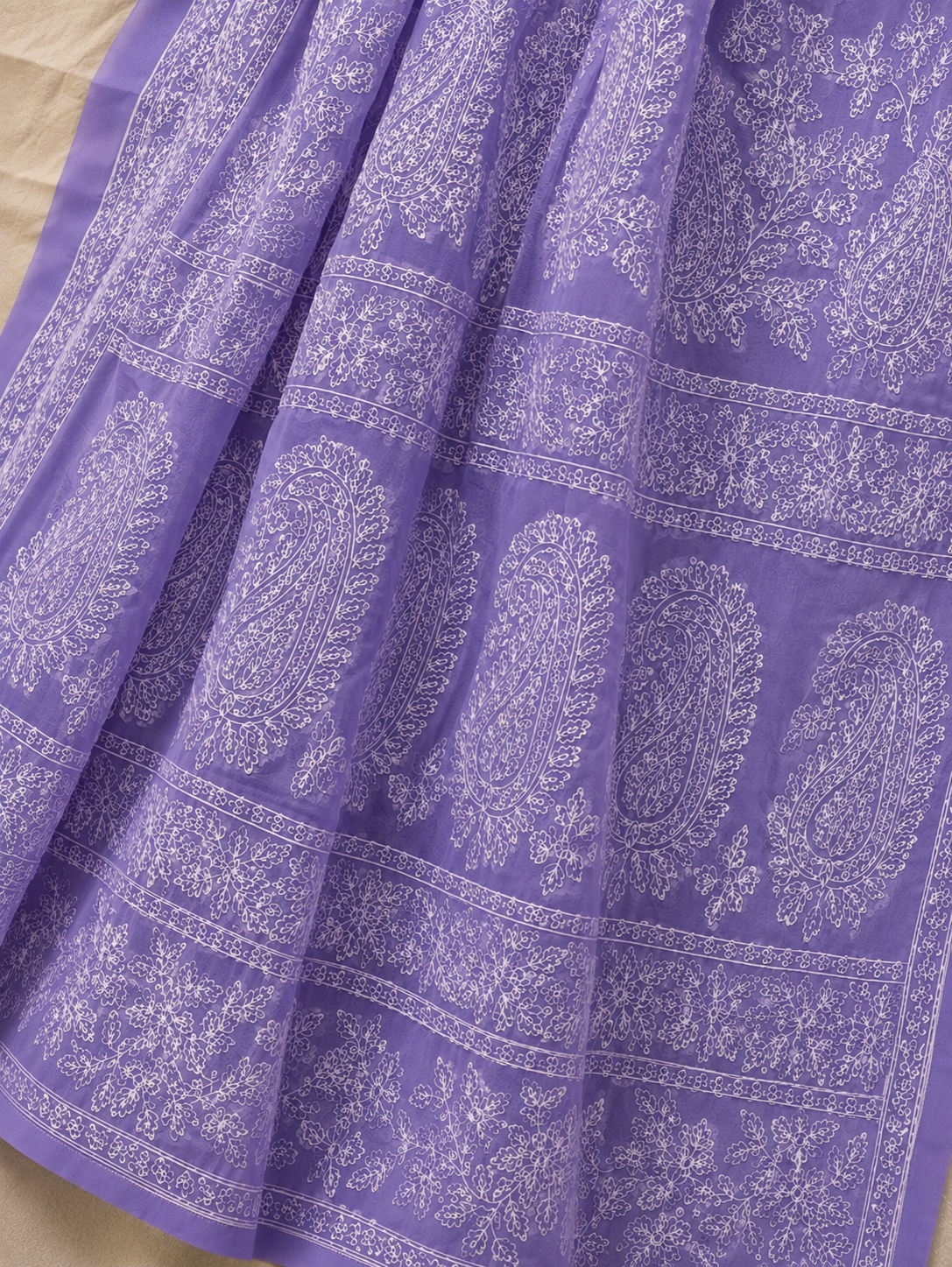 Close-up of a lavender purple pure georgette saree showcasing intricate white floral embroidery, paisley motifs, and elegant embroidered border.