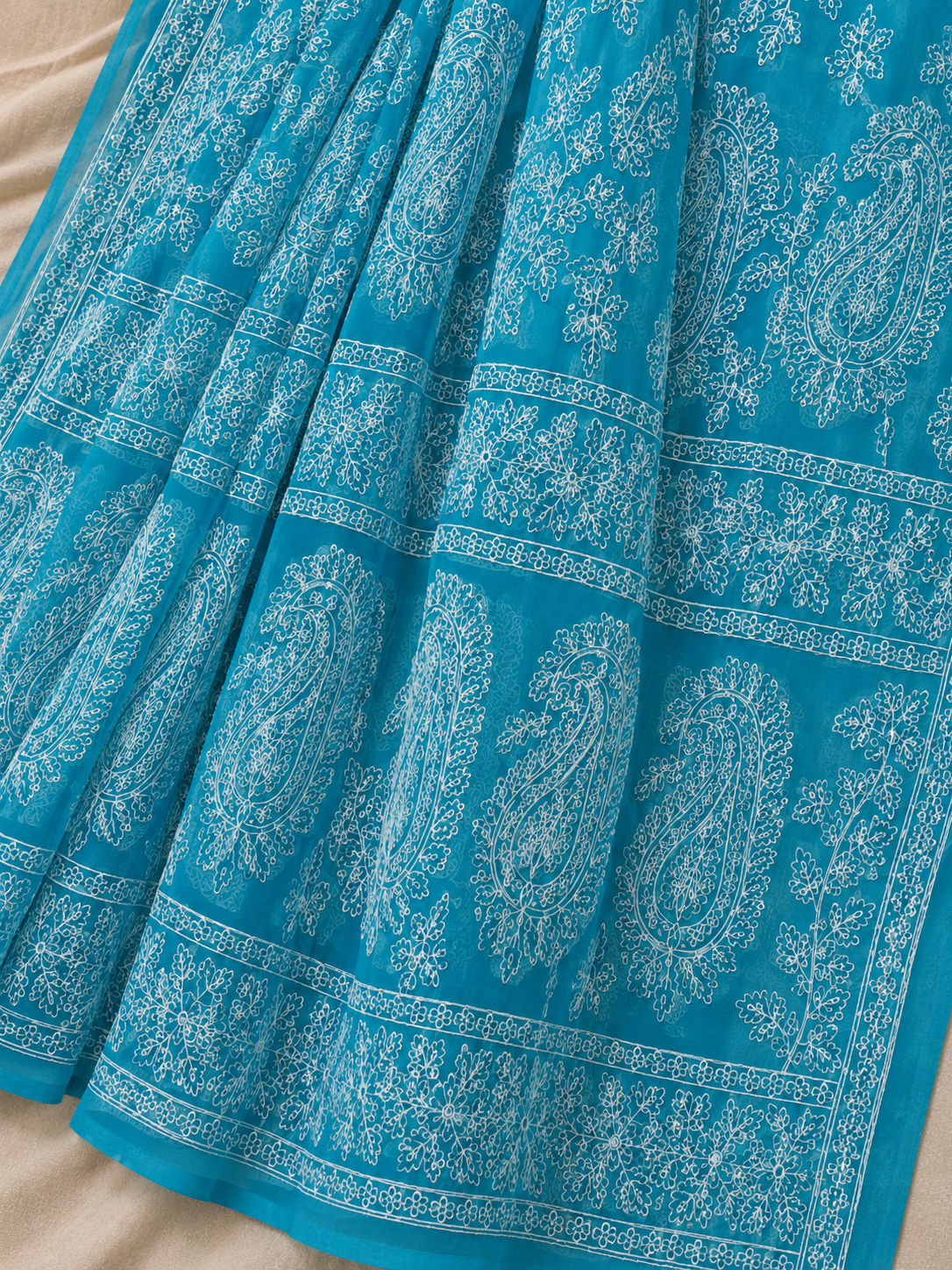 Close-up of a sky blue pure georgette saree highlighting intricate white floral embroidery, paisley motifs, and elegant embroidered border.