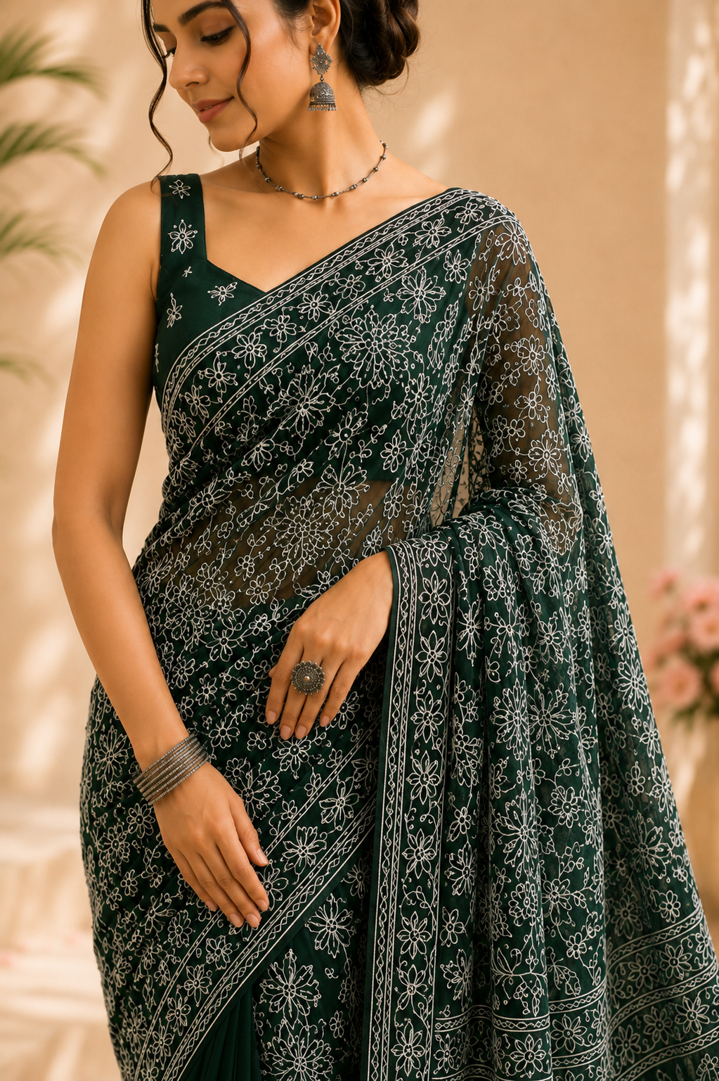 close up a dark green pure georgette saree with detailed white floral embroidery and paisley motifs, styled with a matching embroidered blouse.