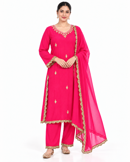 A woman modeling a bright pink traditional Indian salwar kameez suit with gold embroidery and a matching sheer dupatta, photographed against a plain white background.