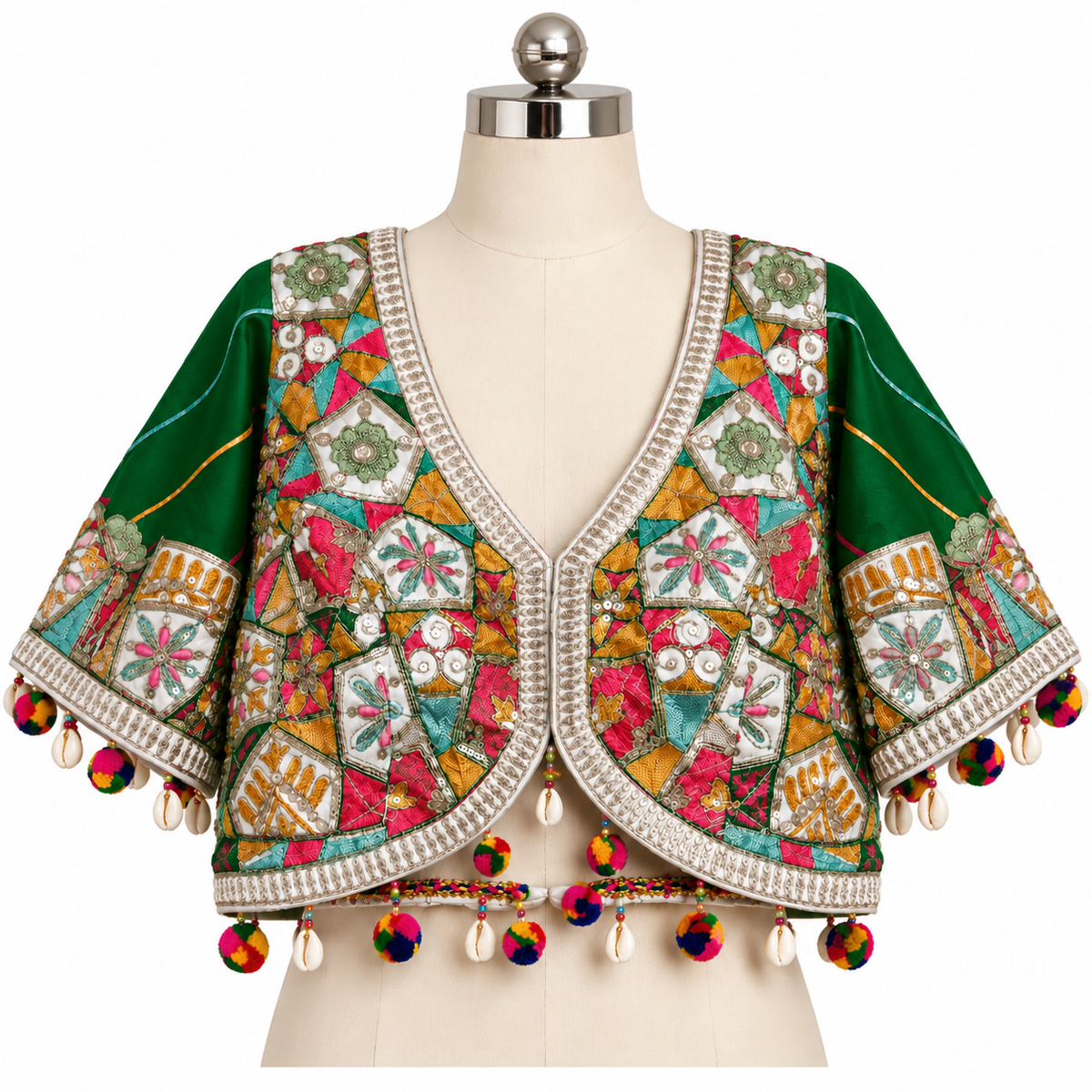 A green embroidered crop jacket with multicolored patchwork embroidery, shell trim, and colorful tassels, displayed on a cream dress form mannequin against a white background.