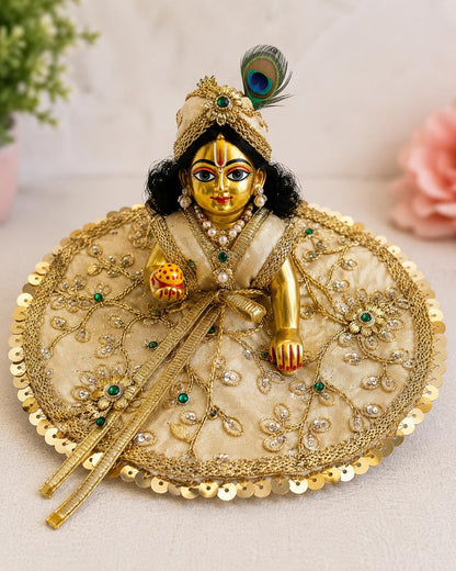 Laddu Gopal wearing an ivory and gold embroidered Janmashtami poshak with peacock feather mukut
