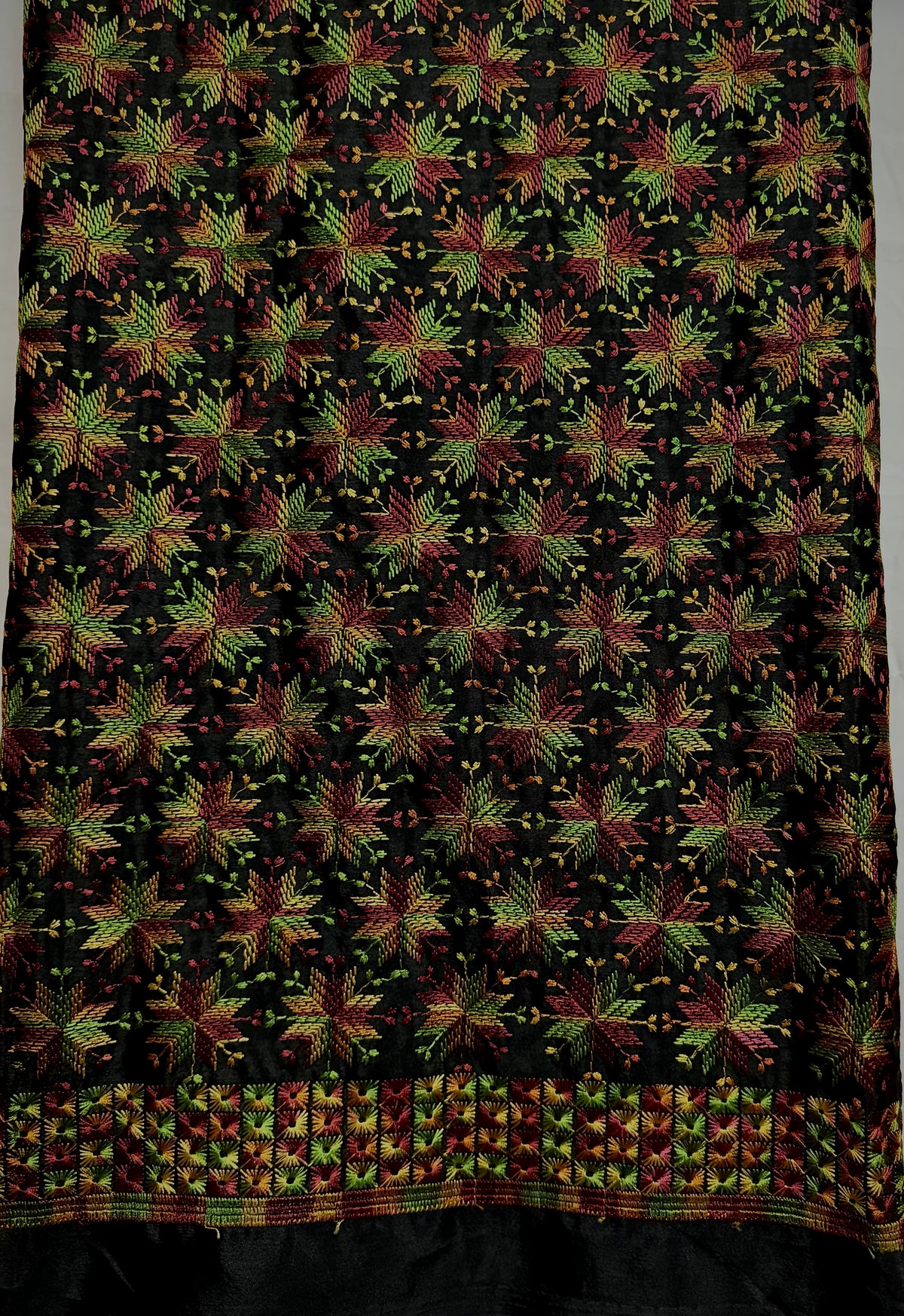 Close-up of jet black Chinnon fabric with multicolor Phulkari-style embroidery