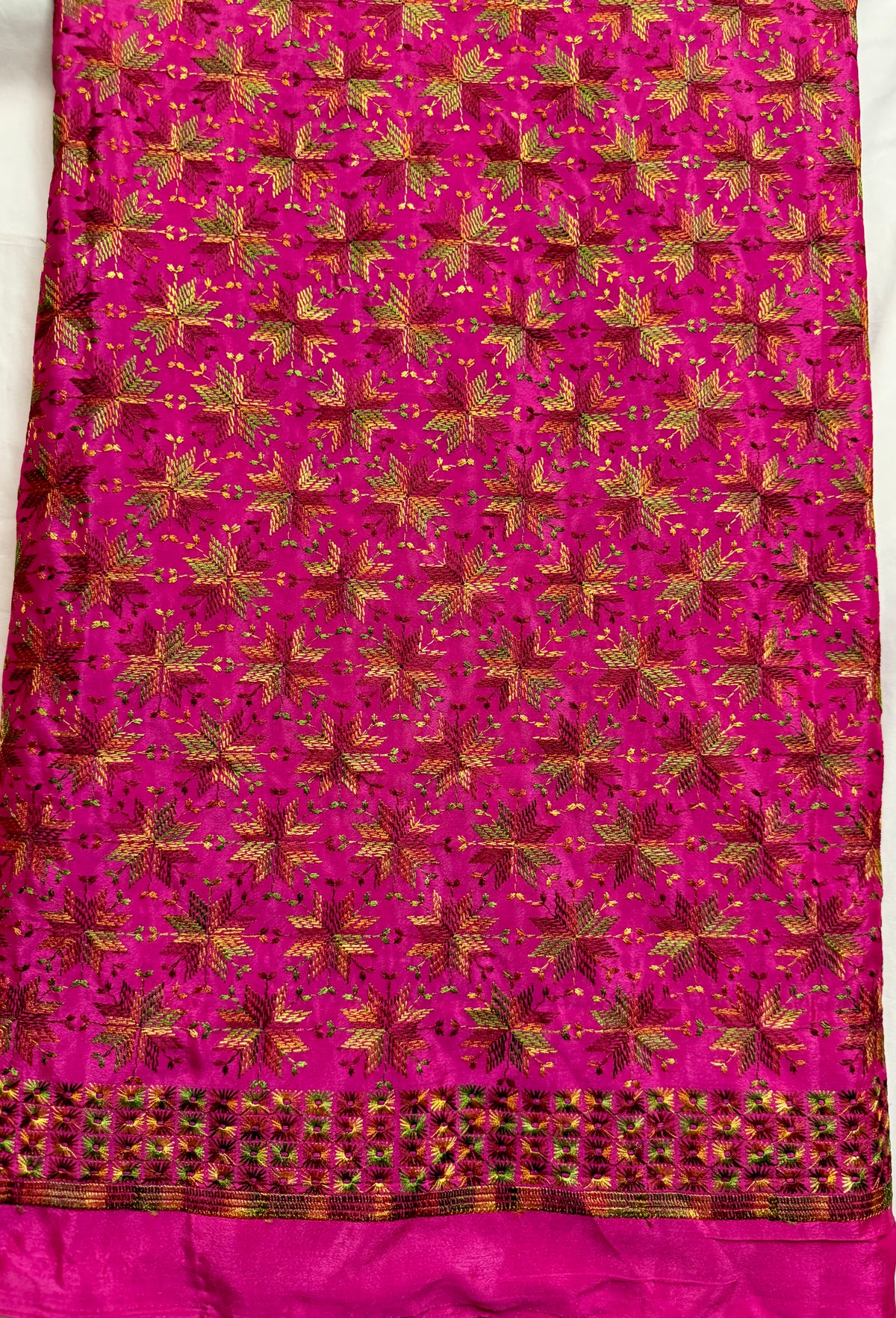 Close-up of magenta Chinnon fabric with multicolor Phulkari-style embroidery