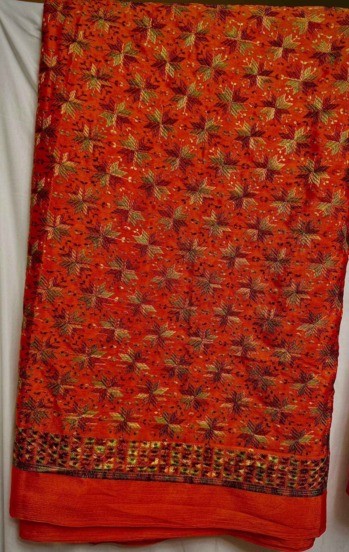 Close-up of orange Chinnon fabric with multicolor Phulkari-style embroidery