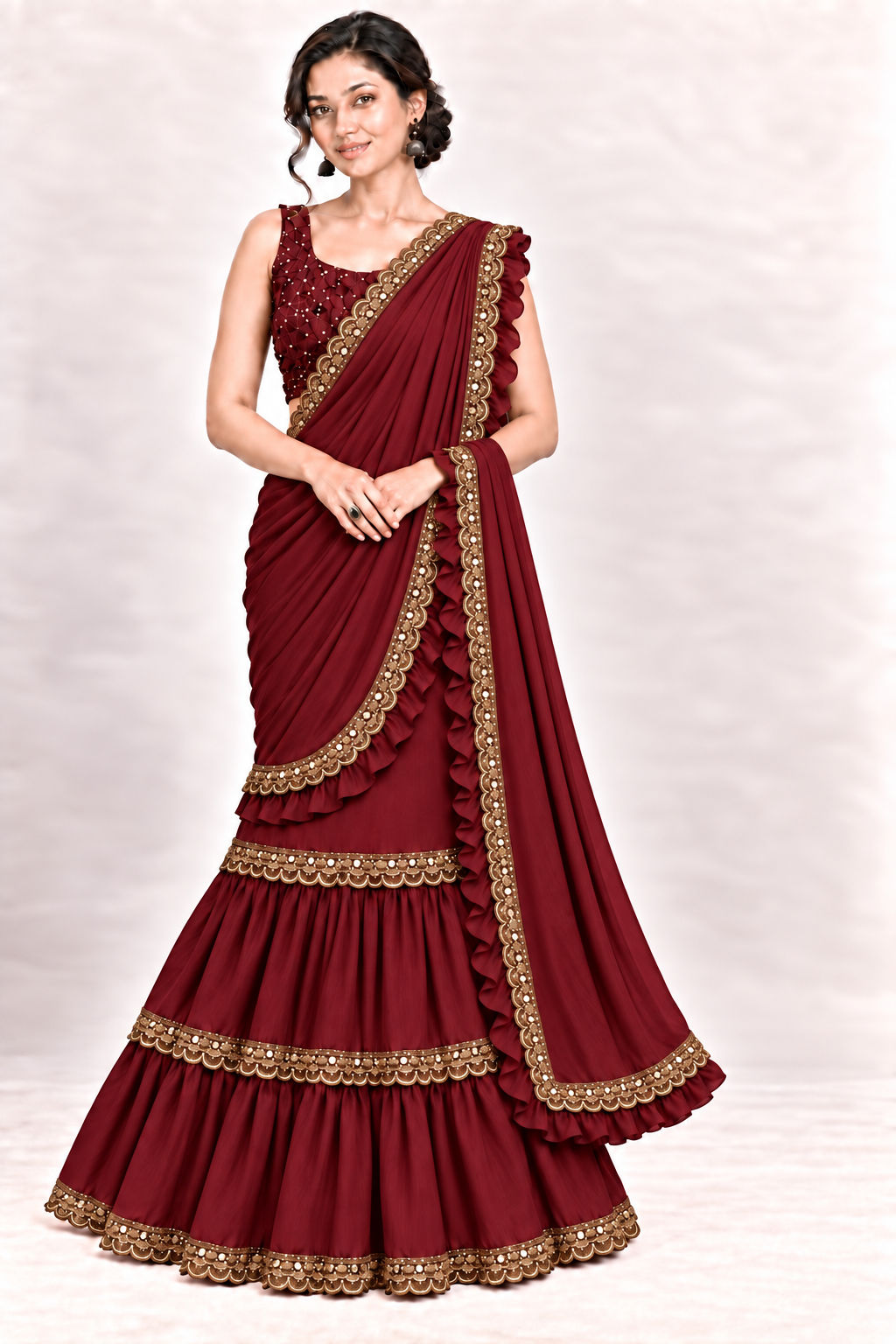 A woman models a deep maroon georgette lehenga choli set with intricate gold embroidery and ruffle details, set against a neutral light gray studio background.