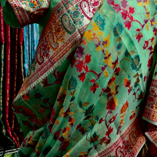 Detailed view of the saree's GreenChanderi silk jacquard fabric with traditional floral and geometric motifs.