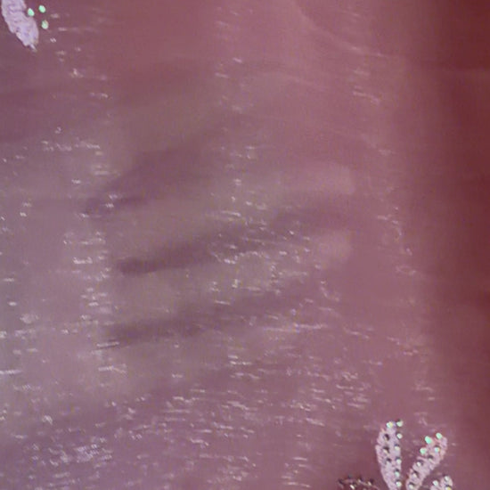 Close-up of peach shimmer tissue chiffon saree fabric showing its soft luminous finish
