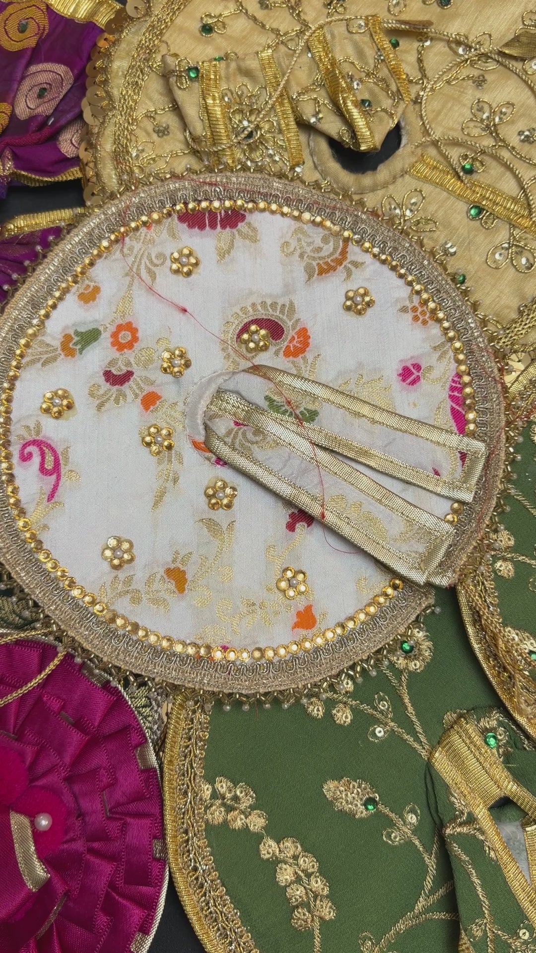 Close-up of colorful Laddu Gopal poshak fabrics with traditional woven patterns and gold embellishments