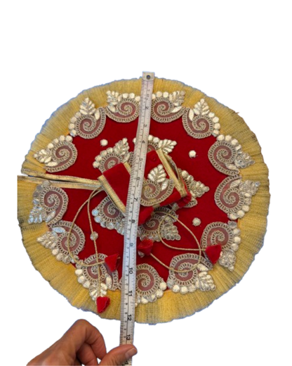 Close-up of red Laddu Gopal poshak featuring gold embroidered paisley motifs and decorative trim